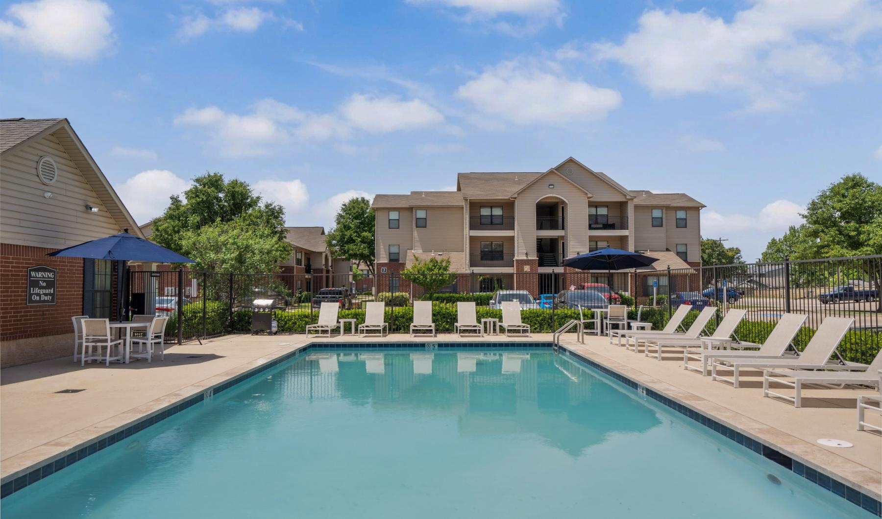 a swimming pool with chairs and umbrellas next to a building