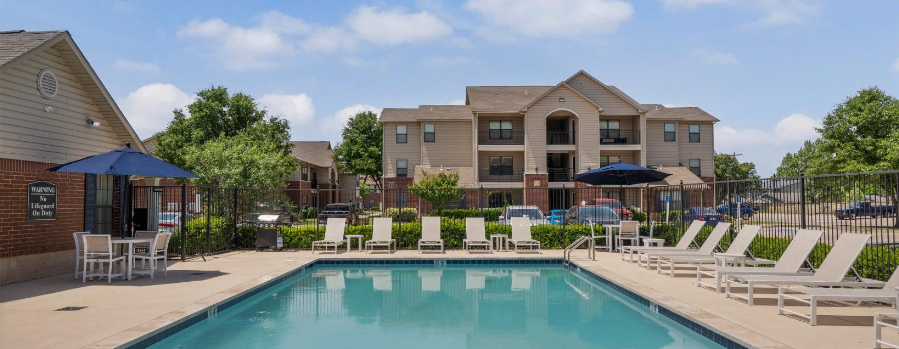 a swimming pool with chairs and umbrellas next to a building